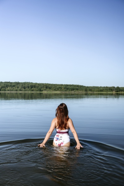 woman walking in lake under blue