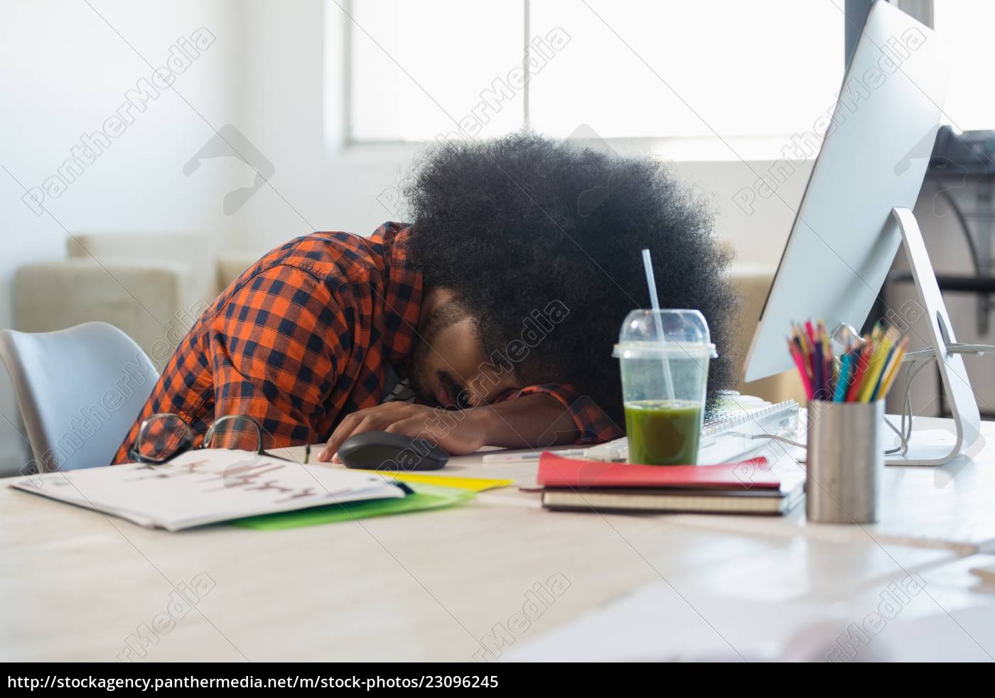 Man With Curly Hair Relaxing At Desk In Office Stock Photo