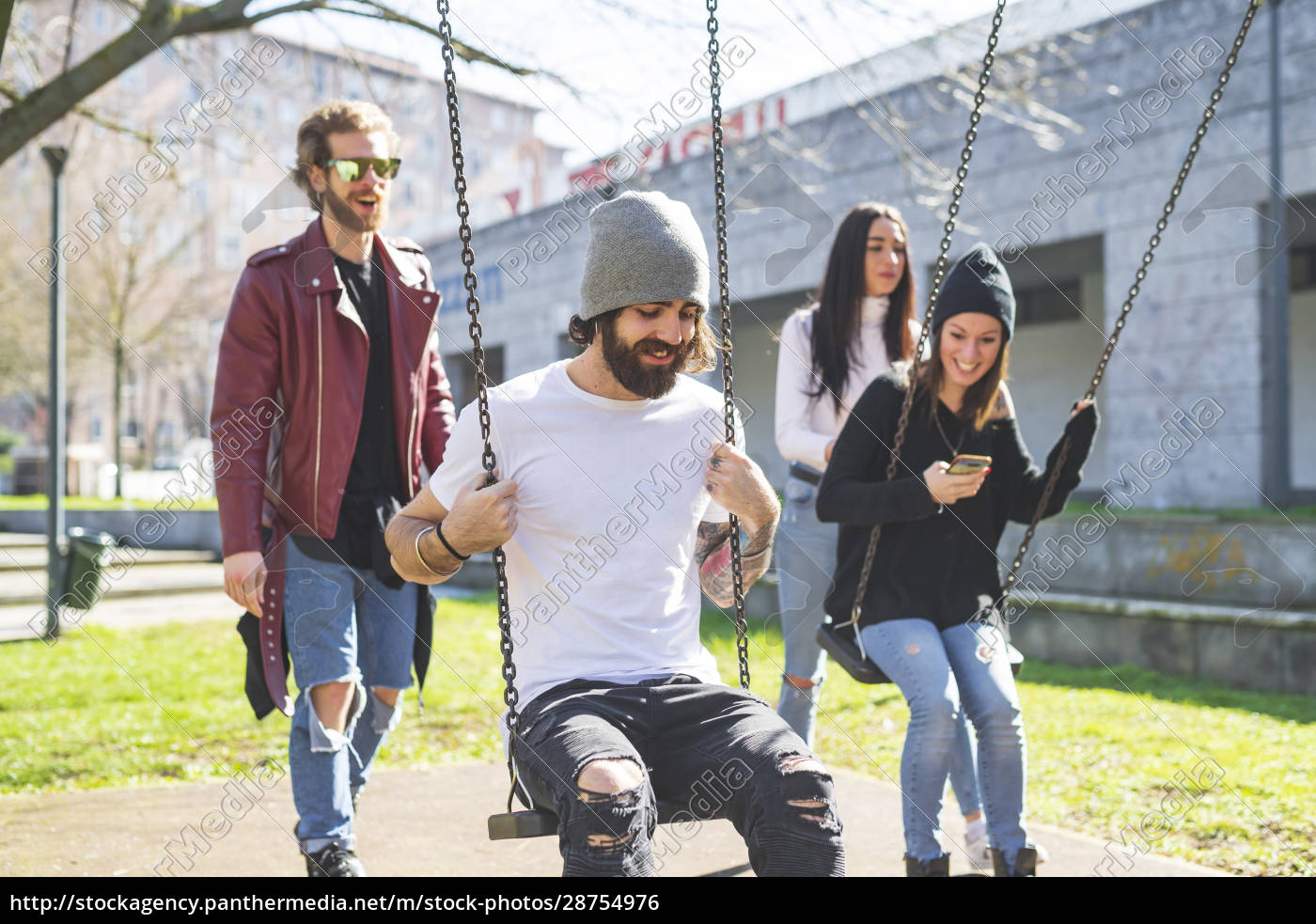 Man and woman pushing friends sitting on swings in - Royalty free photo ...